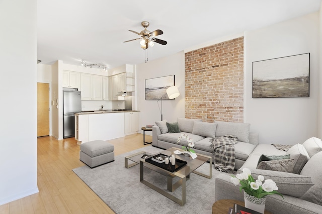 living room featuring brick wall, track lighting, a ceiling fan, and light wood-style floors