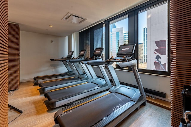 gym with baseboards, visible vents, wood finished floors, and a wealth of natural light