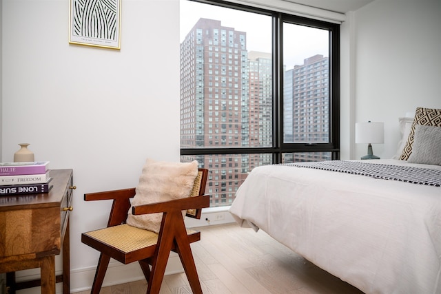 bedroom with baseboards, floor to ceiling windows, a city view, and wood finished floors