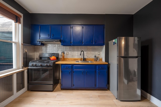 306 Sip Ave Unit 306A, Jersey City, NJ 07306 - kitchen with black range with gas stovetop, freestanding refrigerator, blue cabinetry, under cabinet range hood, and backsplash