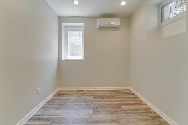 basement with light wood-style floors, a wall mounted AC, plenty of natural light, and recessed lighting