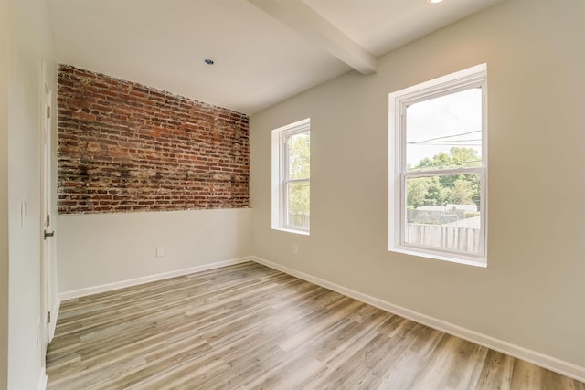 spare room featuring brick wall, light wood-style flooring, baseboards, and beamed ceiling