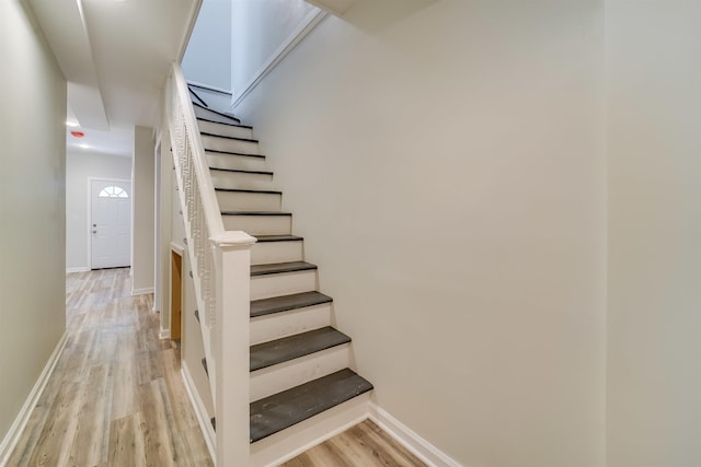 staircase featuring baseboards and wood finished floors