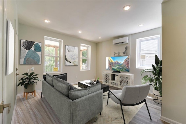 living room featuring a wall mounted AC, wood finished floors, baseboards, and recessed lighting