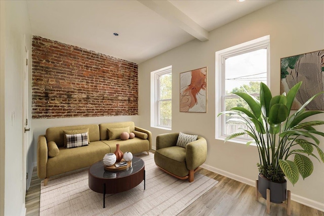 sitting room featuring light wood-style flooring, brick wall, beamed ceiling, and baseboards