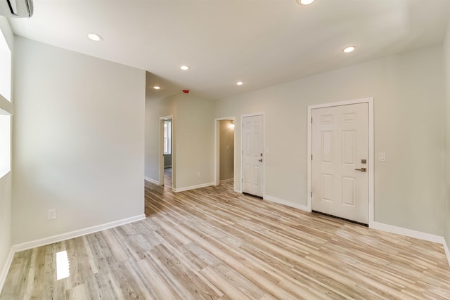 unfurnished room with light wood-style flooring, recessed lighting, baseboards, and a wall mounted air conditioner