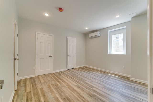 interior space featuring light wood-style flooring, a wall mounted AC, baseboards, and recessed lighting