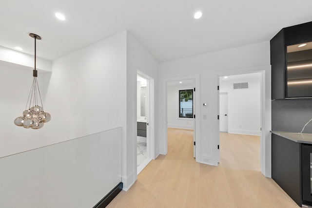 hallway with light hardwood / wood-style floors, a chandelier, and wine cooler