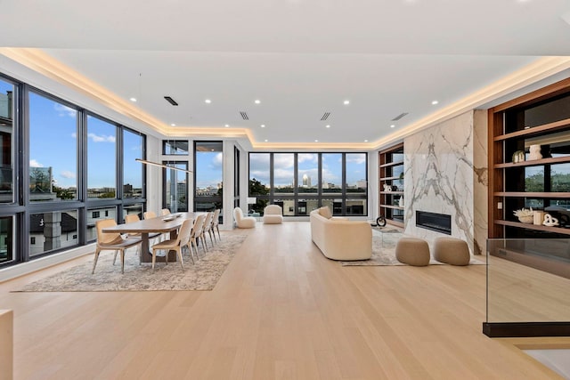 living room featuring a premium fireplace, light wood-type flooring, and floor to ceiling windows