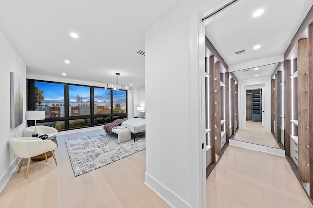 hallway with a chandelier, light wood-type flooring, and floor to ceiling windows