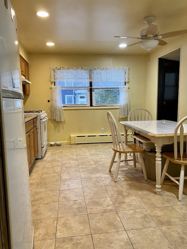 tiled dining area with ceiling fan and baseboard heating