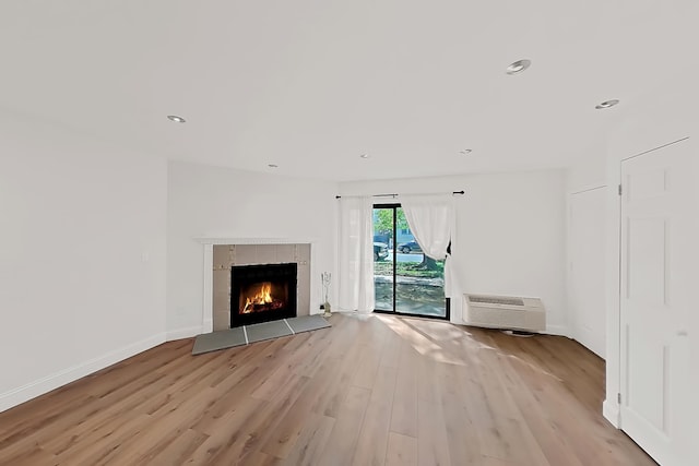 90 Ralph St Unit 3, Belleville, NJ 07109 - unfurnished living room featuring light wood-type flooring, a wall unit AC, a tile fireplace, recessed lighting, and baseboards