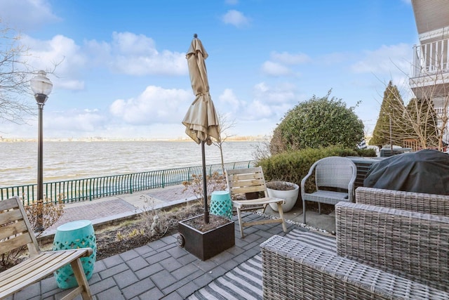 view of patio / terrace featuring an outdoor living space, fence, and a water view