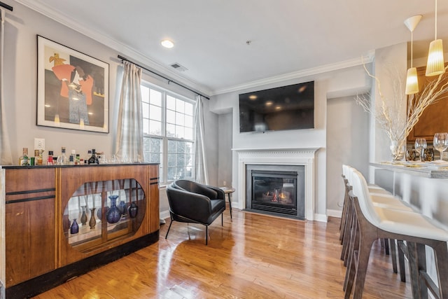 sitting room featuring a glass covered fireplace, visible vents, ornamental molding, and light wood finished floors