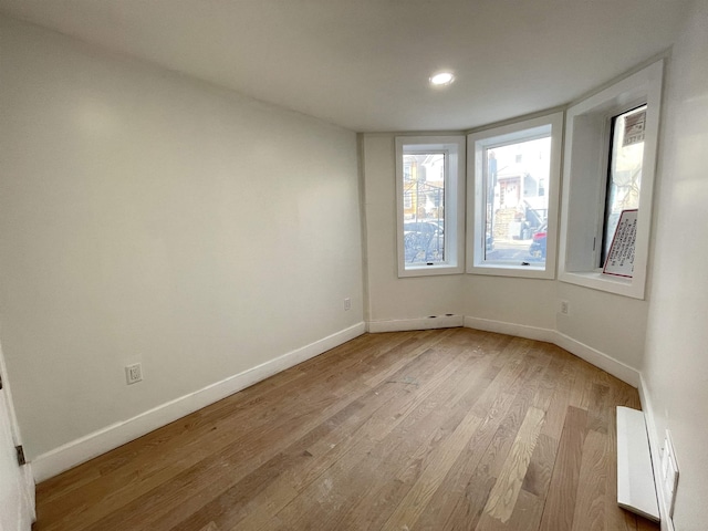 empty room featuring light wood-style floors, visible vents, and baseboards