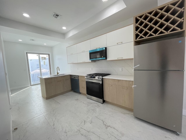 kitchen with visible vents, a peninsula, stainless steel appliances, light countertops, and a sink