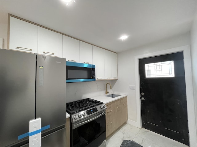 kitchen featuring white cabinets, appliances with stainless steel finishes, marble finish floor, light countertops, and a sink