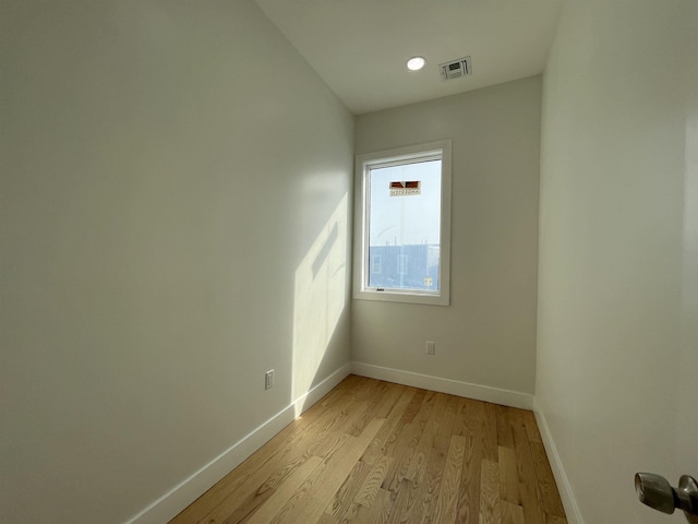 spare room with light wood-type flooring, visible vents, and baseboards