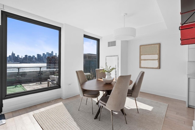 dining space with baseboards, a view of city, visible vents, and wood finished floors