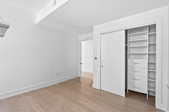 unfurnished bedroom with a closet, baseboards, and wood finished floors