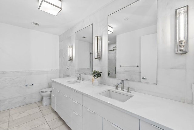 bathroom with a sink, tile walls, toilet, and an enclosed shower