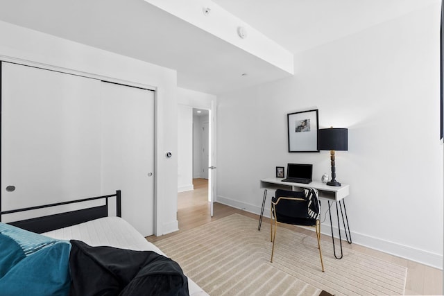 bedroom featuring a closet, light wood-style flooring, and baseboards