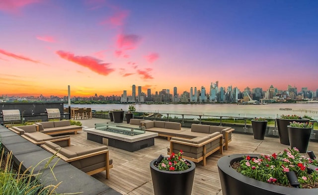 deck featuring an outdoor living space with a fire pit, a city view, a water view, an outdoor kitchen, and a grill