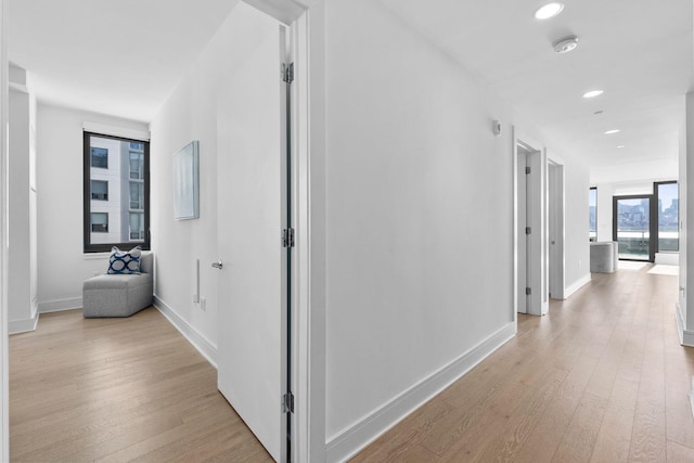 hallway with light wood-type flooring, baseboards, and recessed lighting