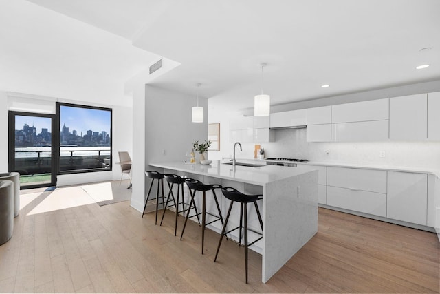 kitchen featuring light wood finished floors, modern cabinets, visible vents, and a breakfast bar