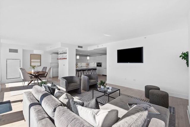 living area featuring wood finished floors, visible vents, and baseboards