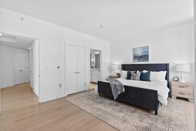 bedroom featuring light wood-type flooring, ensuite bath, and baseboards