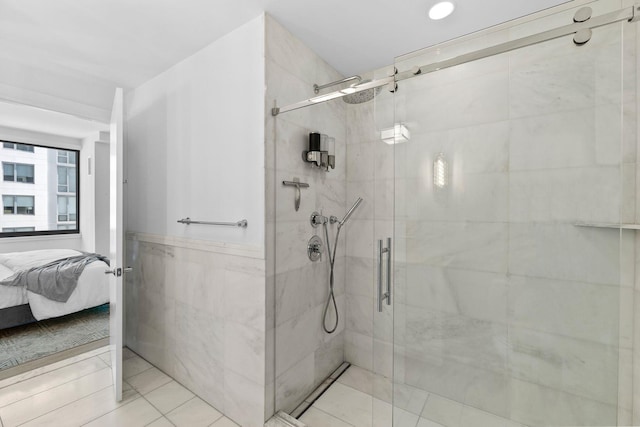 ensuite bathroom with a stall shower, wainscoting, tile walls, and ensuite bath