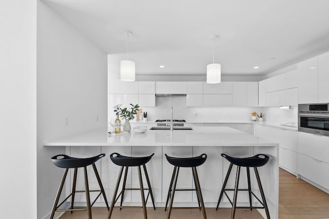 kitchen with a breakfast bar area, oven, white cabinetry, tasteful backsplash, and modern cabinets