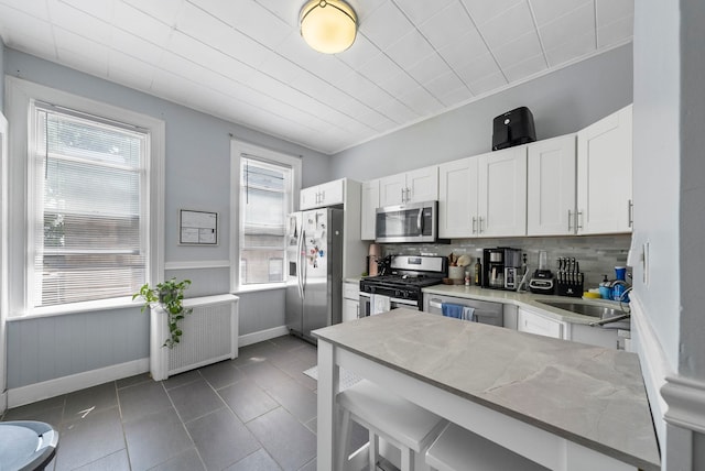 57 Booraem Ave, Jersey City, NJ 07307 - kitchen featuring stainless steel appliances, radiator, white cabinets, tasteful backsplash, and dark tile patterned floors