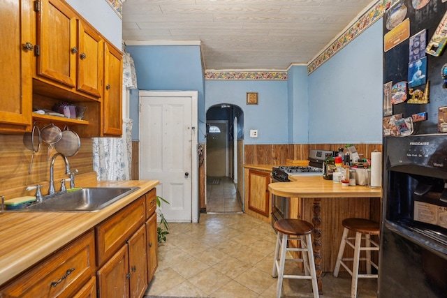 442 Avenue E Ave E, Bayonne, NJ 07002 - kitchen featuring black refrigerator with ice dispenser, a sink, a wainscoted wall, range with gas stovetop, and arched walkways