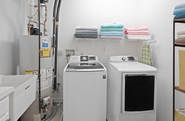 laundry room with laundry area, separate washer and dryer, gas water heater, and a sink