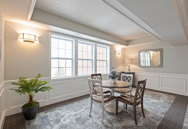 dining space featuring a wainscoted wall, a decorative wall, and a raised ceiling