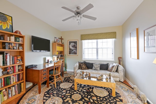 living area with ceiling fan and baseboards