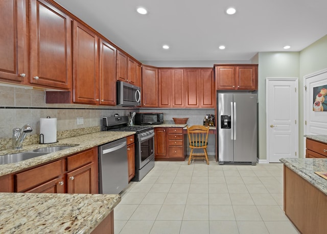 kitchen with light stone counters, tasteful backsplash, recessed lighting, appliances with stainless steel finishes, and a sink