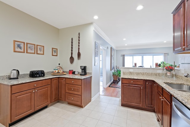 kitchen with light stone counters, a sink, a peninsula, and stainless steel dishwasher