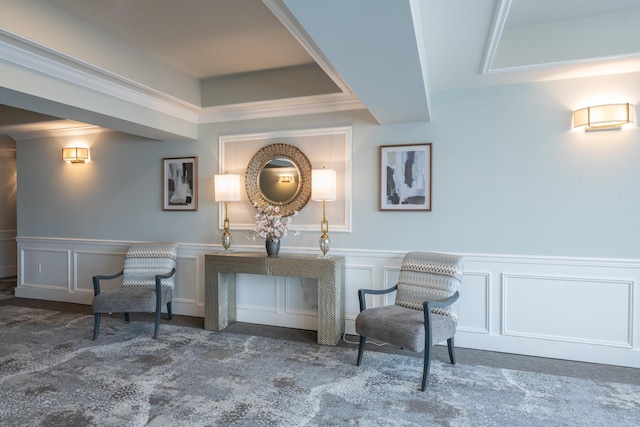 sitting room with carpet floors, wainscoting, and a decorative wall