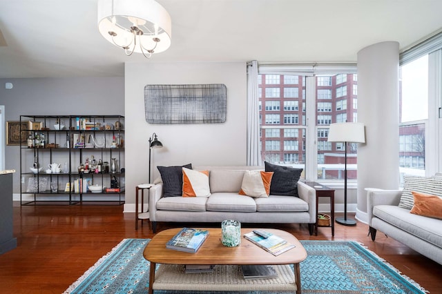 living area featuring baseboards, an inviting chandelier, and wood finished floors