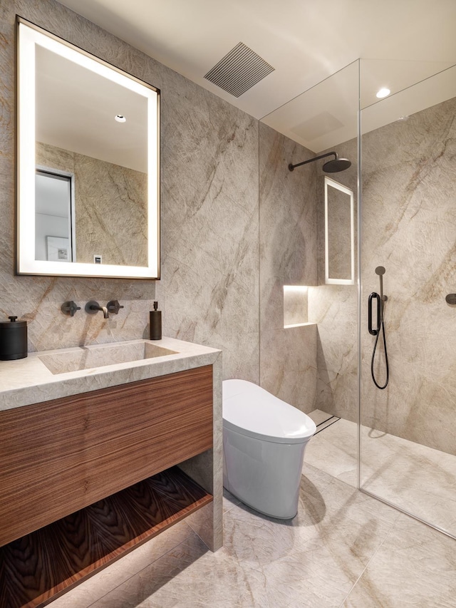 bathroom with a tile shower, vanity, and toilet