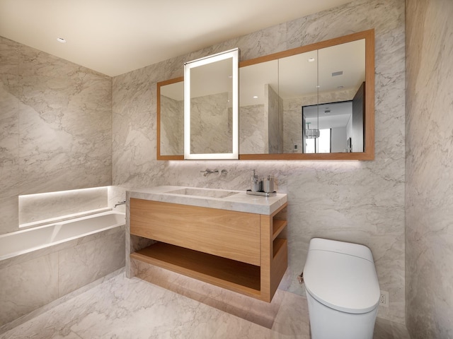 bathroom featuring vanity, tiled bath, toilet, and tile walls