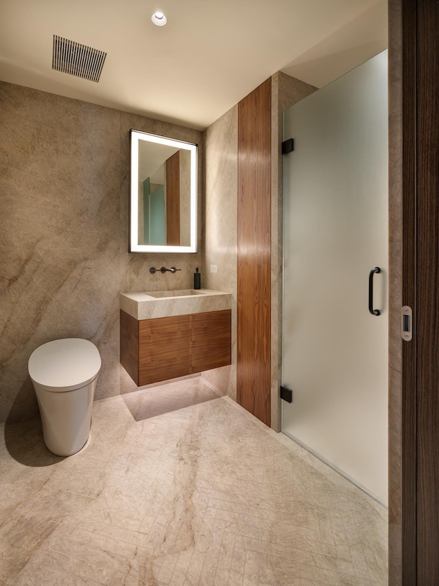 bathroom with a shower with door, vanity, tile walls, and toilet