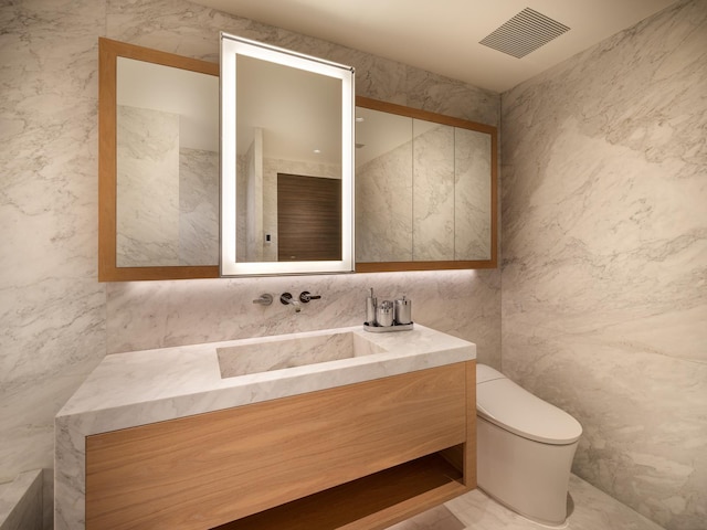 bathroom featuring vanity, toilet, and tile walls