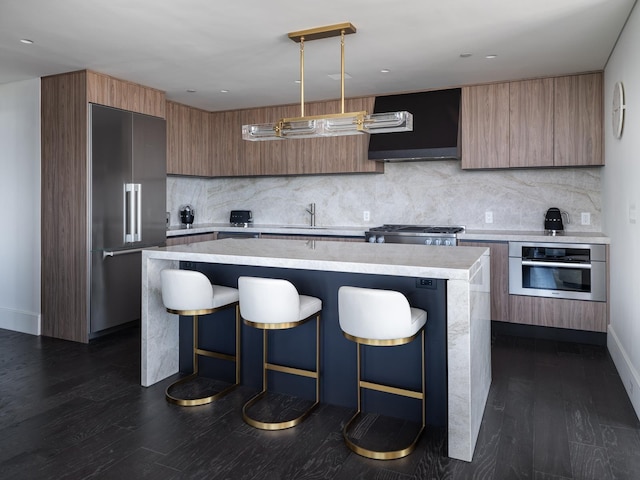 kitchen featuring appliances with stainless steel finishes, extractor fan, decorative light fixtures, a center island, and a breakfast bar area