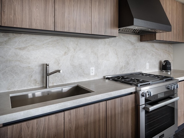 kitchen featuring wall chimney exhaust hood, decorative backsplash, sink, and stainless steel stove