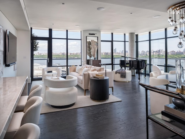 living room with dark hardwood / wood-style floors, an inviting chandelier, a wall of windows, and a water view