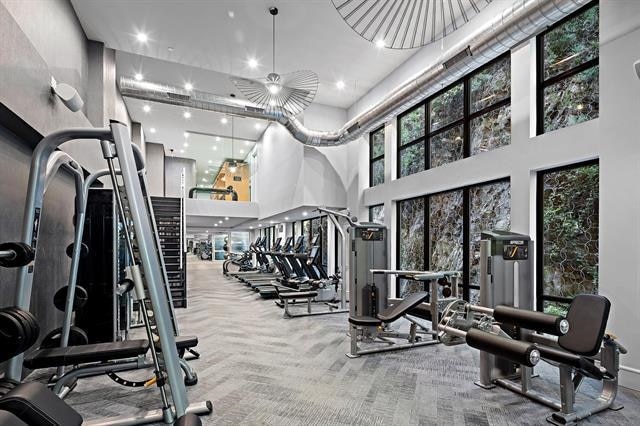 exercise room with light carpet and a towering ceiling